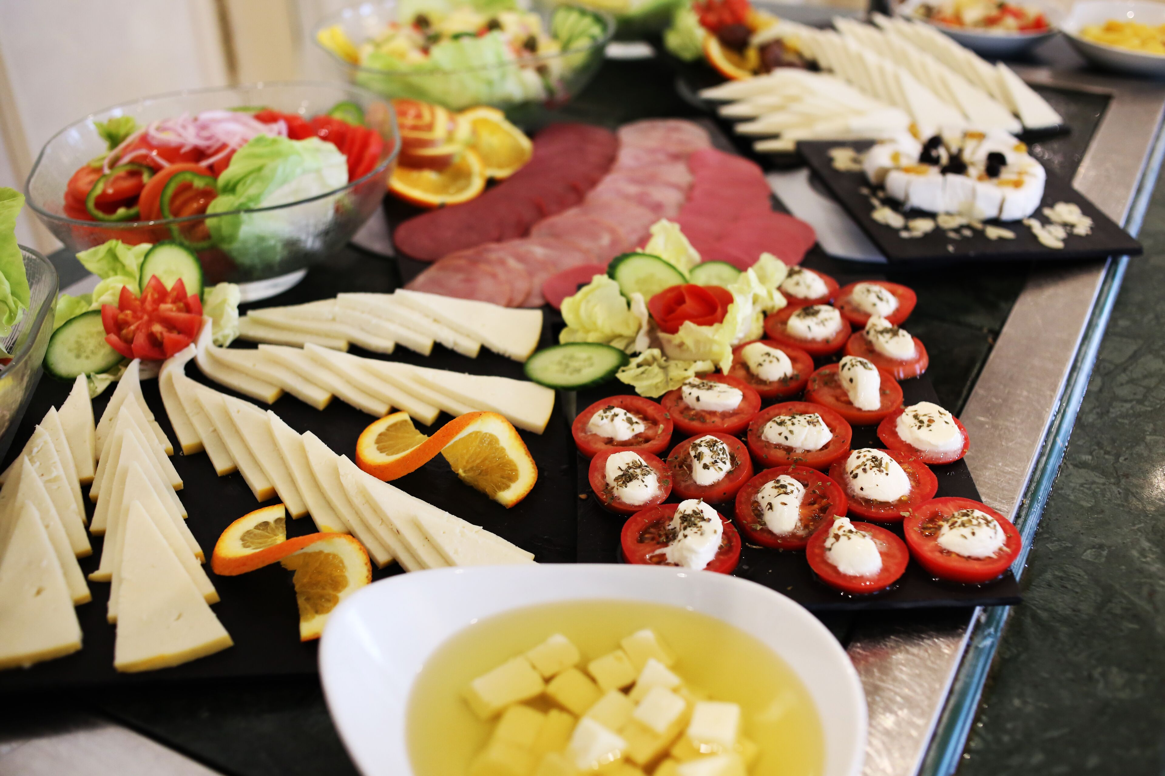 A buffet with various cheeses, cured meats, and a bowl of soup.