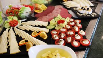 A buffet with various cheeses, cured meats, and a bowl of soup.