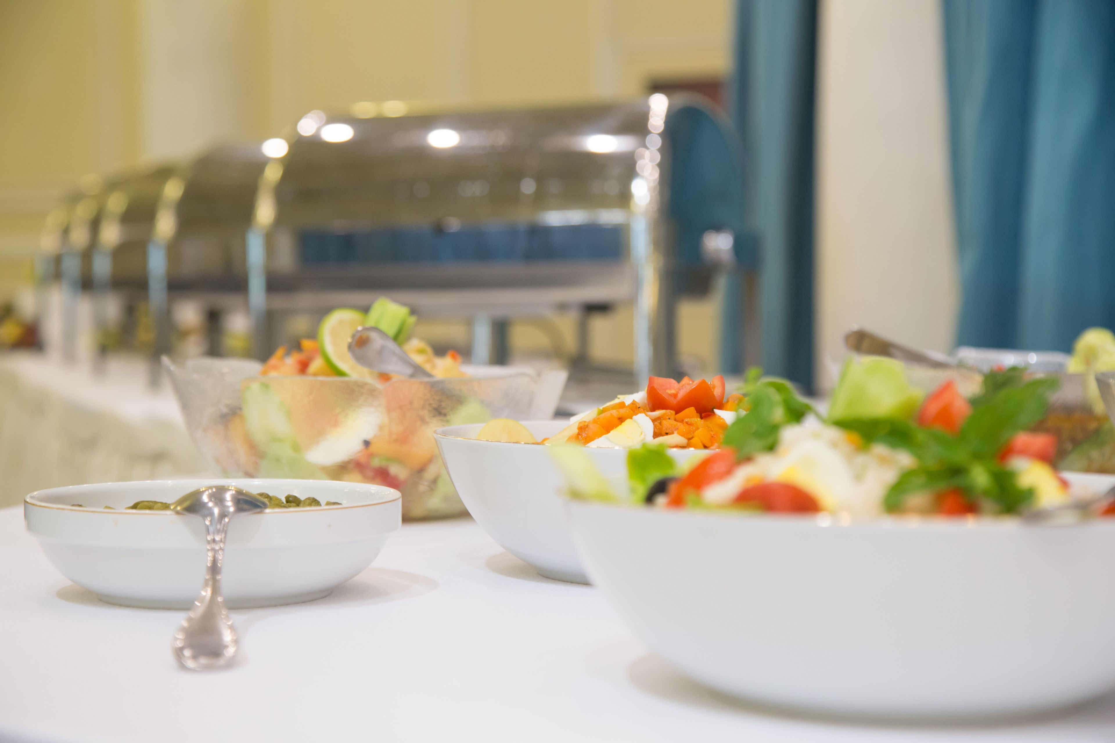 Une table de buffet avec différents plats de salade et une cuillère.