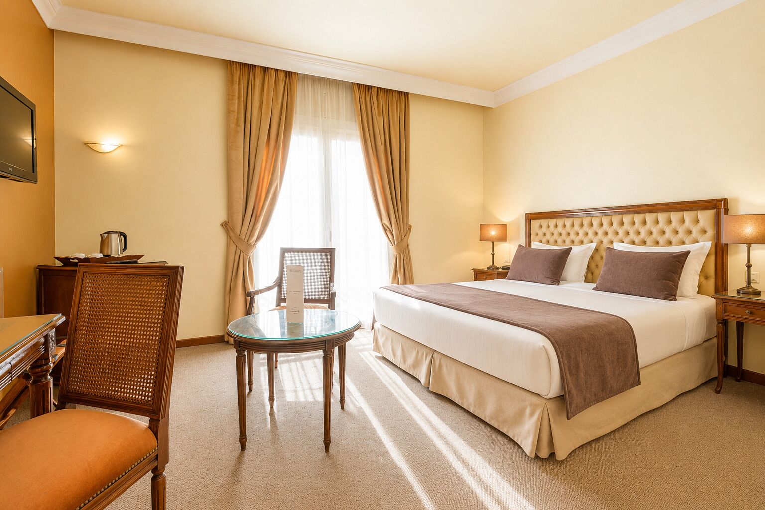 A hotel room with a bed, a chair, a small table, a lamp, and a television.