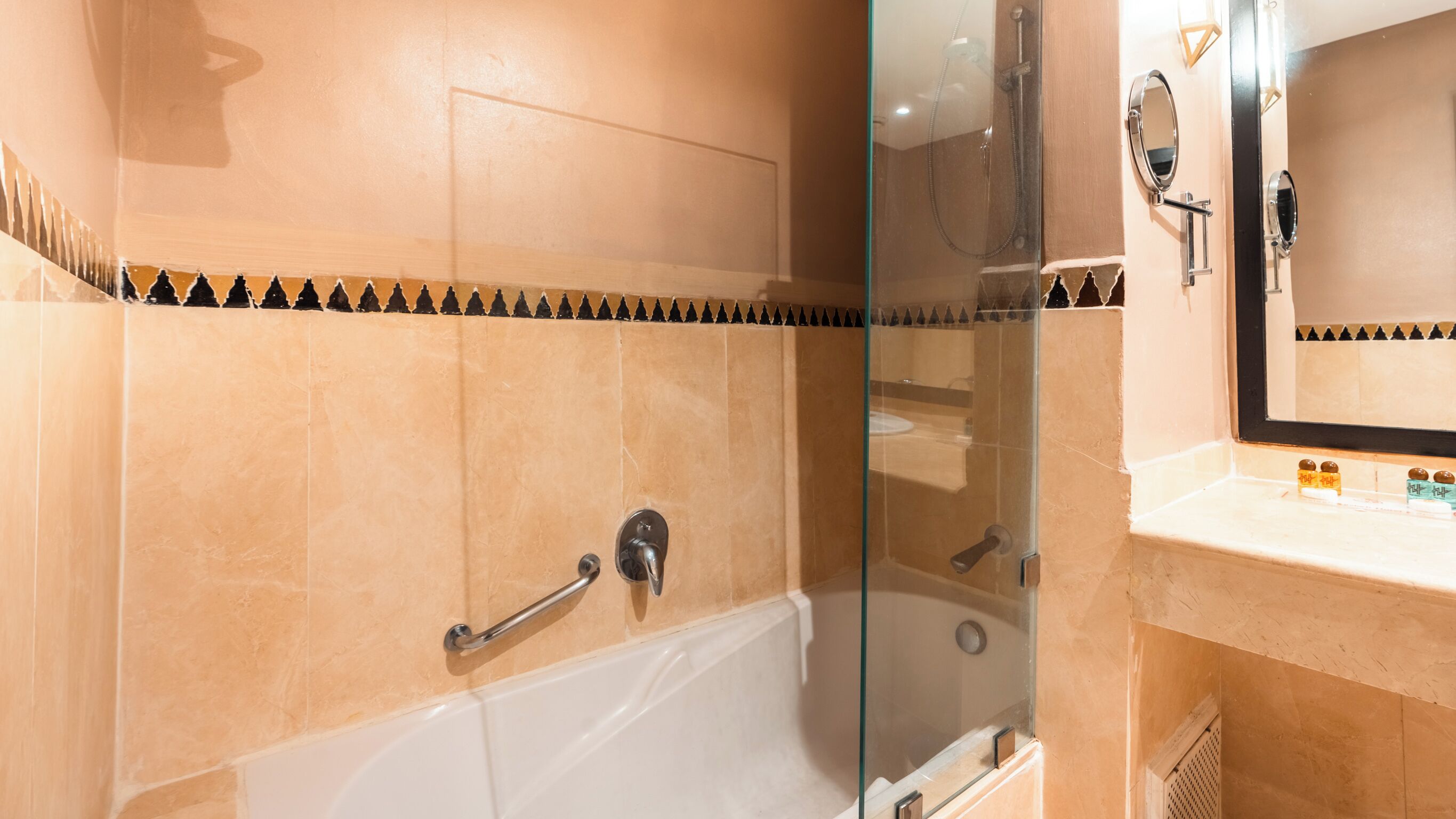 Un baño con bañera, cabina de ducha de vidrio, tocador con espejo y perchero para toallas.