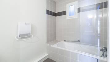 Une salle de bain avec une baignoire blanche, un porte-serviettes et un radiateur fixé au mur.
