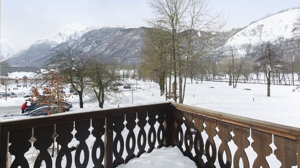 A snow-covered balcony with a view of a snowy landscape and mountains.