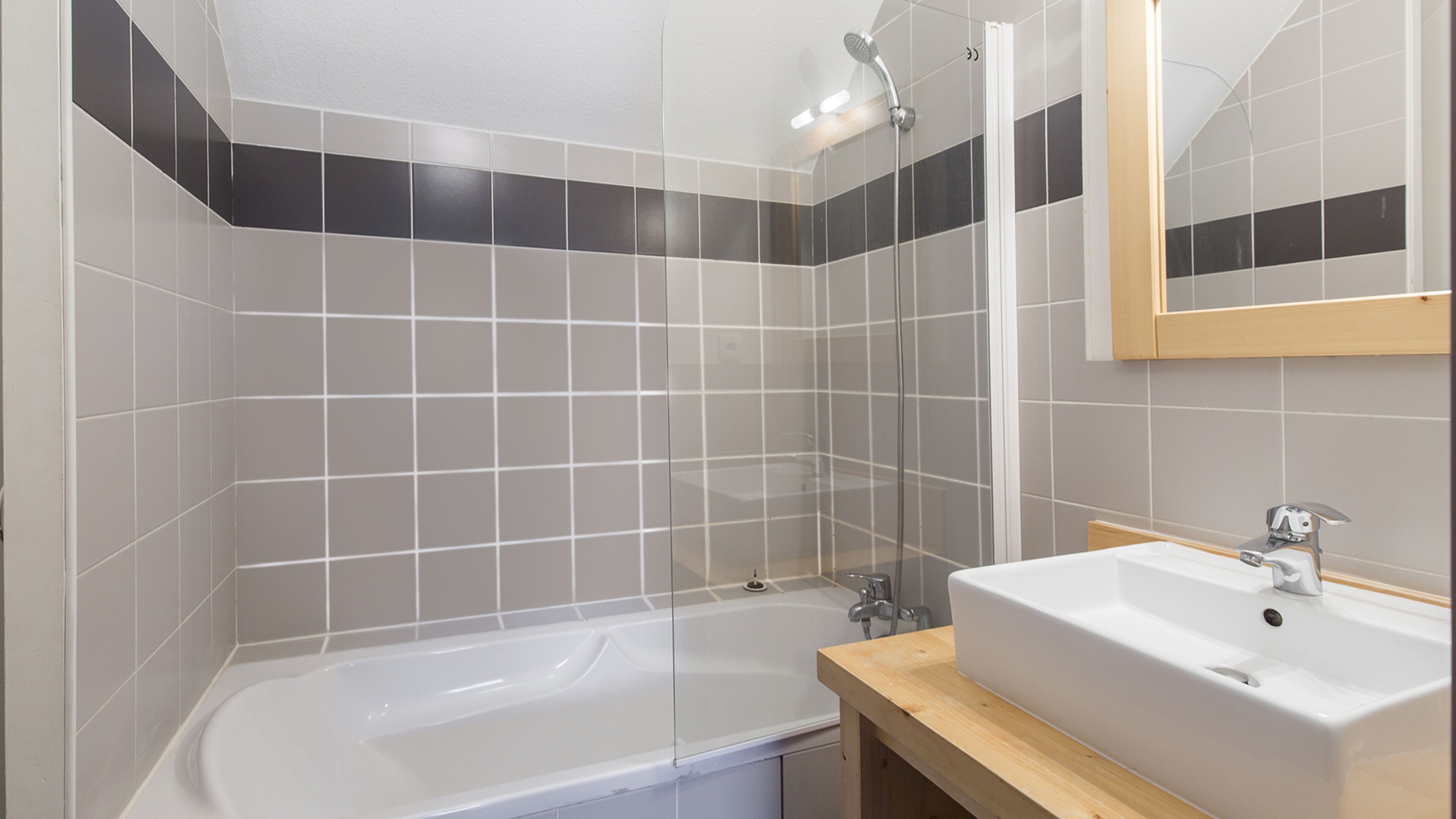 Een moderne badkamer met een bad, wastafel en douche.