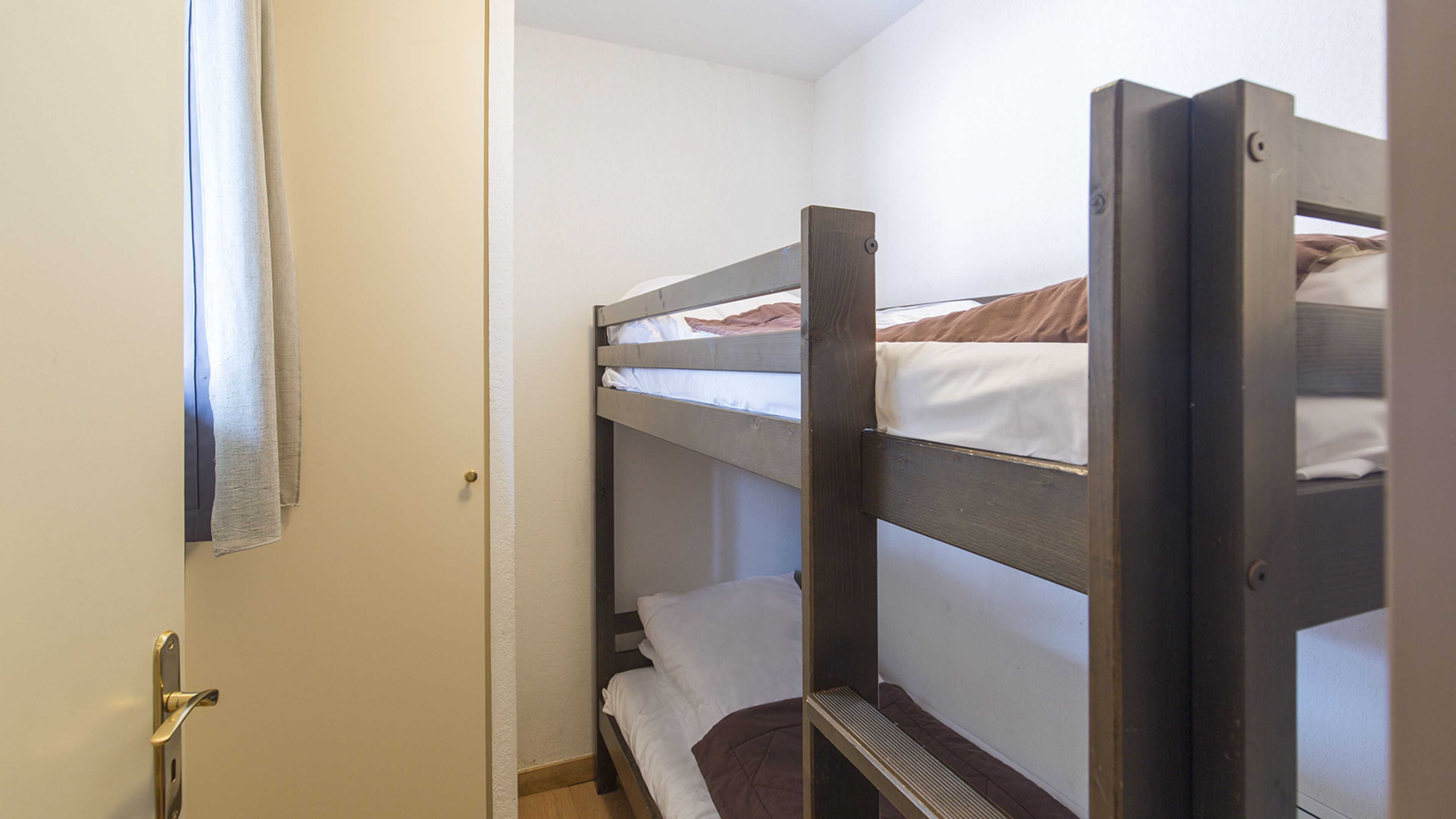 A bunk bed room with a door and a window.