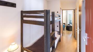 A bunk bed room with a wooden frame, a bedside table, and a lamp.