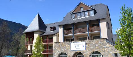A multi-story hotel with a stone facade, multiple balconies, and a prominent tower-like structure.