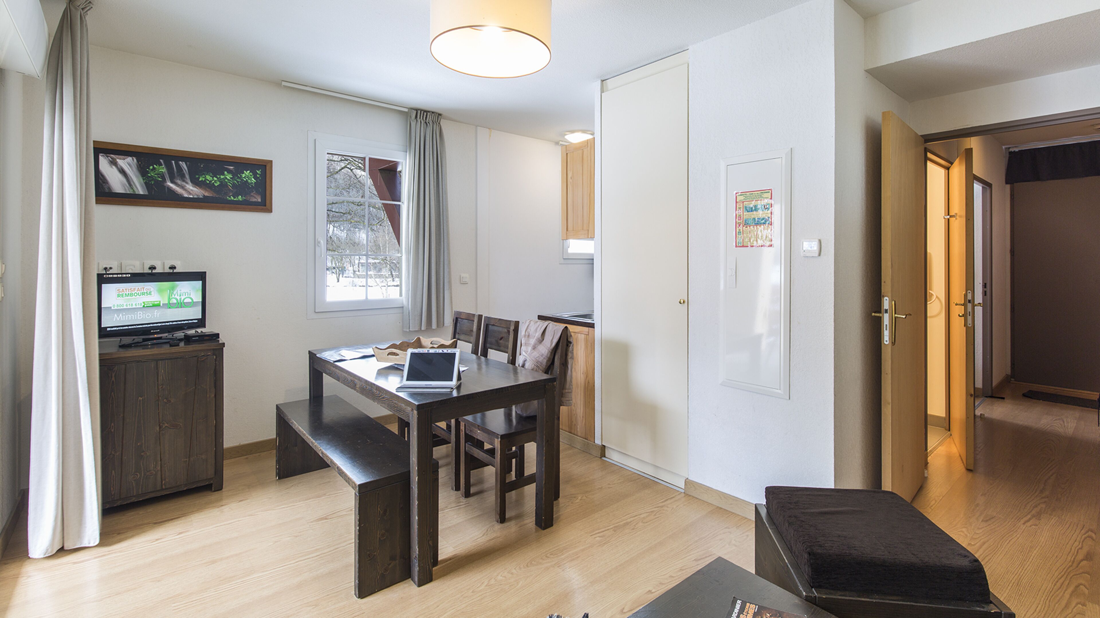A compact living space with a dining area, a television, and a kitchenette.
