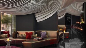 A modern interior with a curved ceiling design, a seating area with cushions, and a reflective floor. - The Washington (New York)