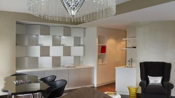 A modern living room with a dining area, a chandelier, and a black armchair.