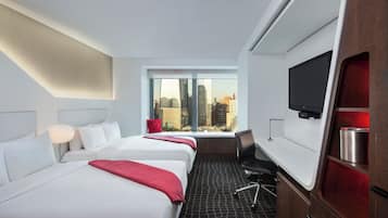 Habitación de hotel con dos camas, televisión, escritorio y ventana con vista a la ciudad.