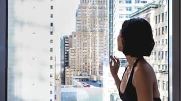 Una persona sentada junto a una ventana con vistas a edificios altos.