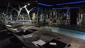 A modern indoor pool area with lounge chairs and a unique ceiling structure. - A Point Arezzo Park Hotel (Arezzo)