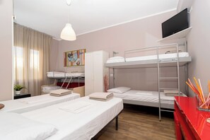 Un dormitorio con literas, un escritorio con una silla roja, un televisor en la pared y un cuadro colgado.