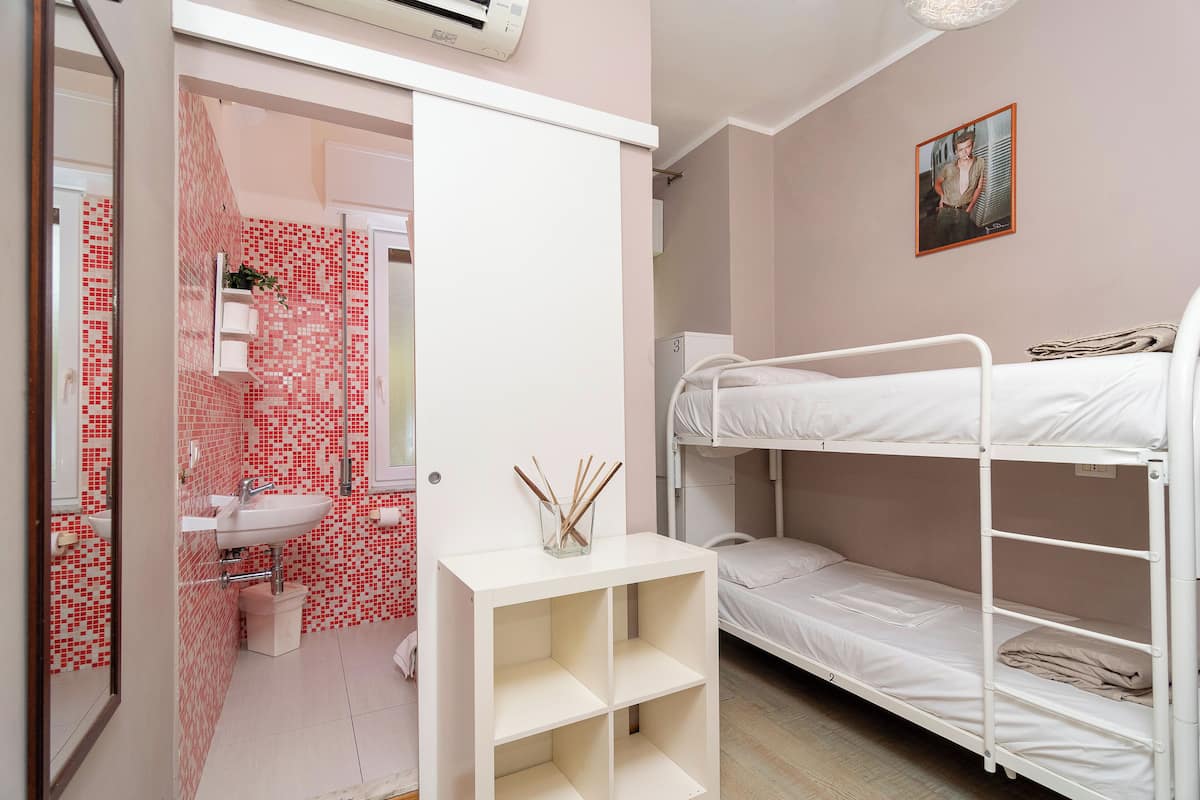Ein Zimmer mit Etagenbett, Waschbecken und Fliesenwand.