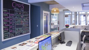 A reception desk with a chalkboard listing daily activities and prices, a computer, and a modern interior design. - Circus Hotel & Hostel (Buenos Aires)