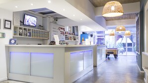 A hotel reception area with a check-in counter, a television, and a sign indicating the exit. - Circus Hotel & Hostel (Buenos Aires)