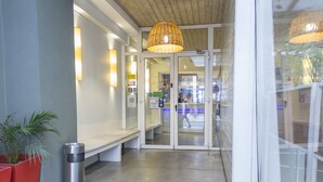 A hotel entrance with a bench, a trash bin, a wicker lamp, and a doormat with the word "CIRCUS". - Circus Hotel & Hostel (Buenos Aires)