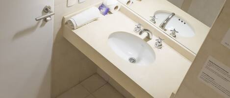 A small, modern bathroom with a toilet, two sinks, and a mirror.