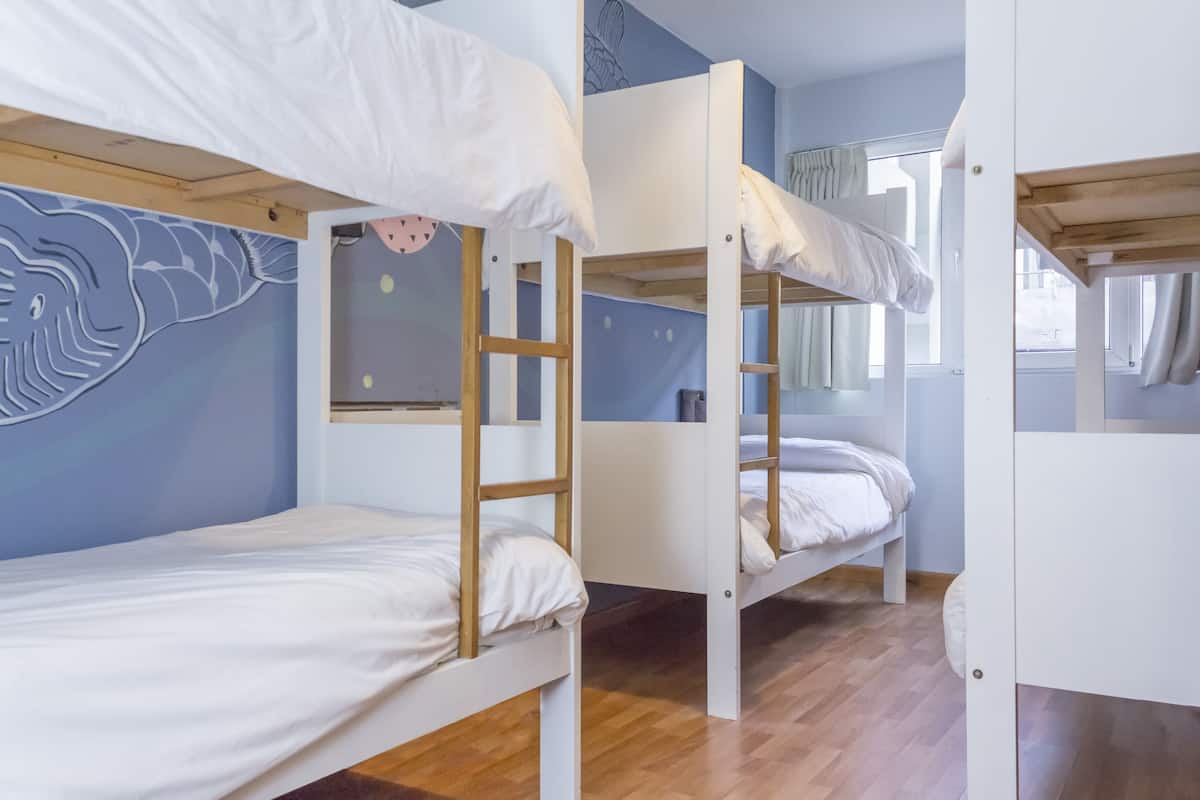 Quarto com beliches de madeira e roupa de cama branca.