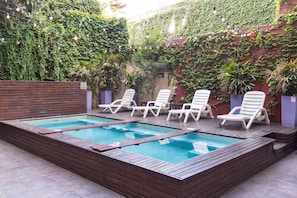 A rectangular swimming pool with wooden deck and white lounge chairs. - Circus Hotel & Hostel (Buenos Aires)