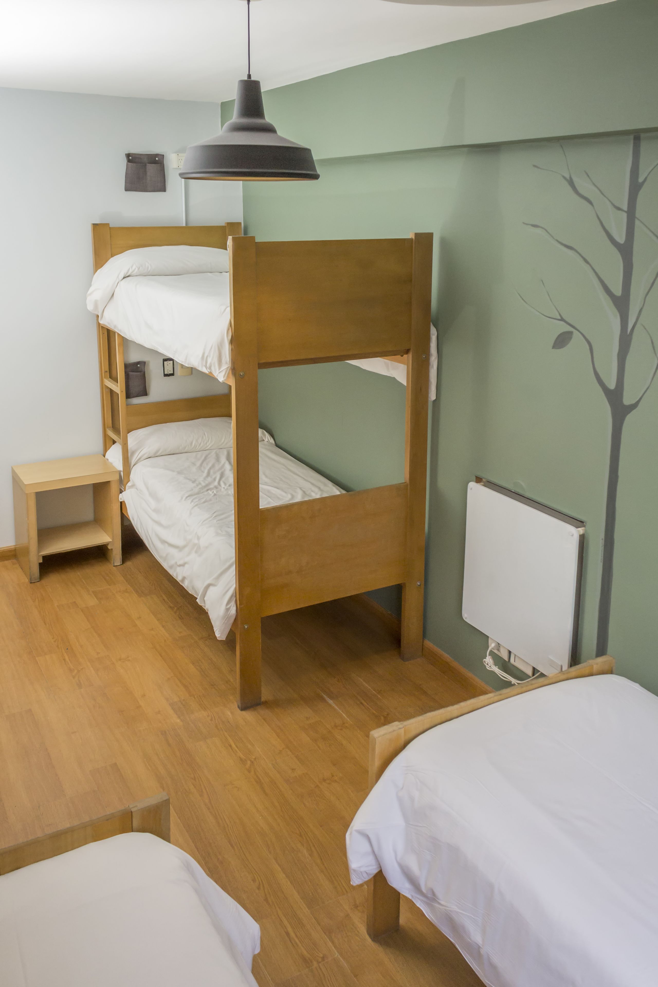 A bunk bed room with a wooden headboard, a bedside table, and a hanging lamp.
