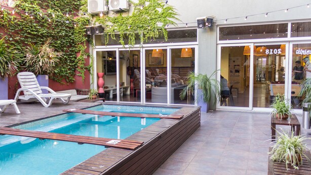 A pool area with a wooden deck, lounge chairs, and potted plants. - Circus Hotel & Hostel (Buenos Aires)