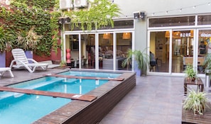A pool area with a wooden deck, lounge chairs, and potted plants. - Circus Hotel & Hostel (Buenos Aires)