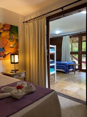 A hotel room with a bed, a nightstand, a painting, and a view of a balcony with a hammock. - ThalassaGarden Hotel - Pousada (Tibau do Sul)