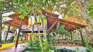 Un espacio al aire libre cubierto, con estructura de madera, rodeado de abundante vegetación y árboles.