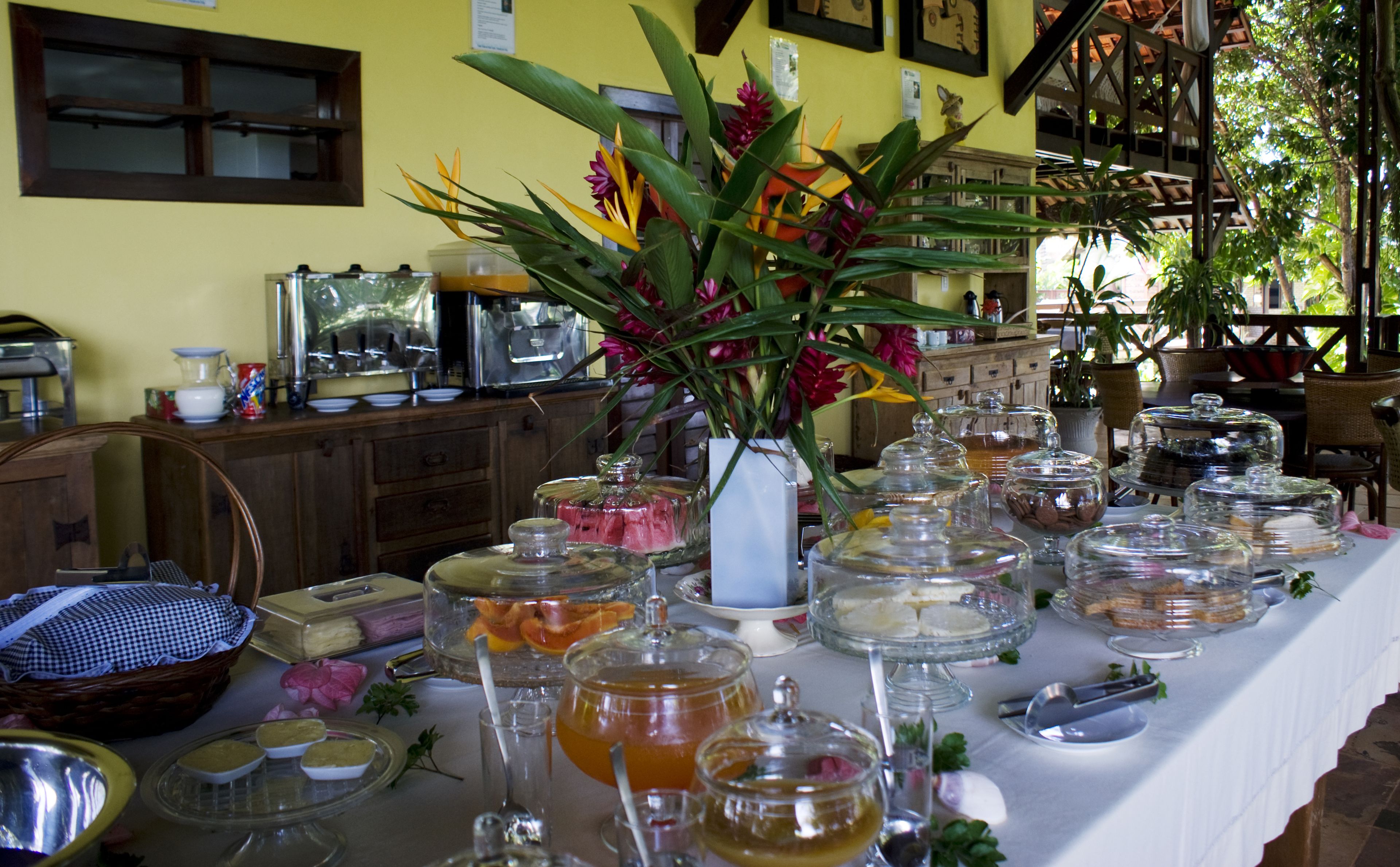 A buffet table with various food items and a vase of flowers.