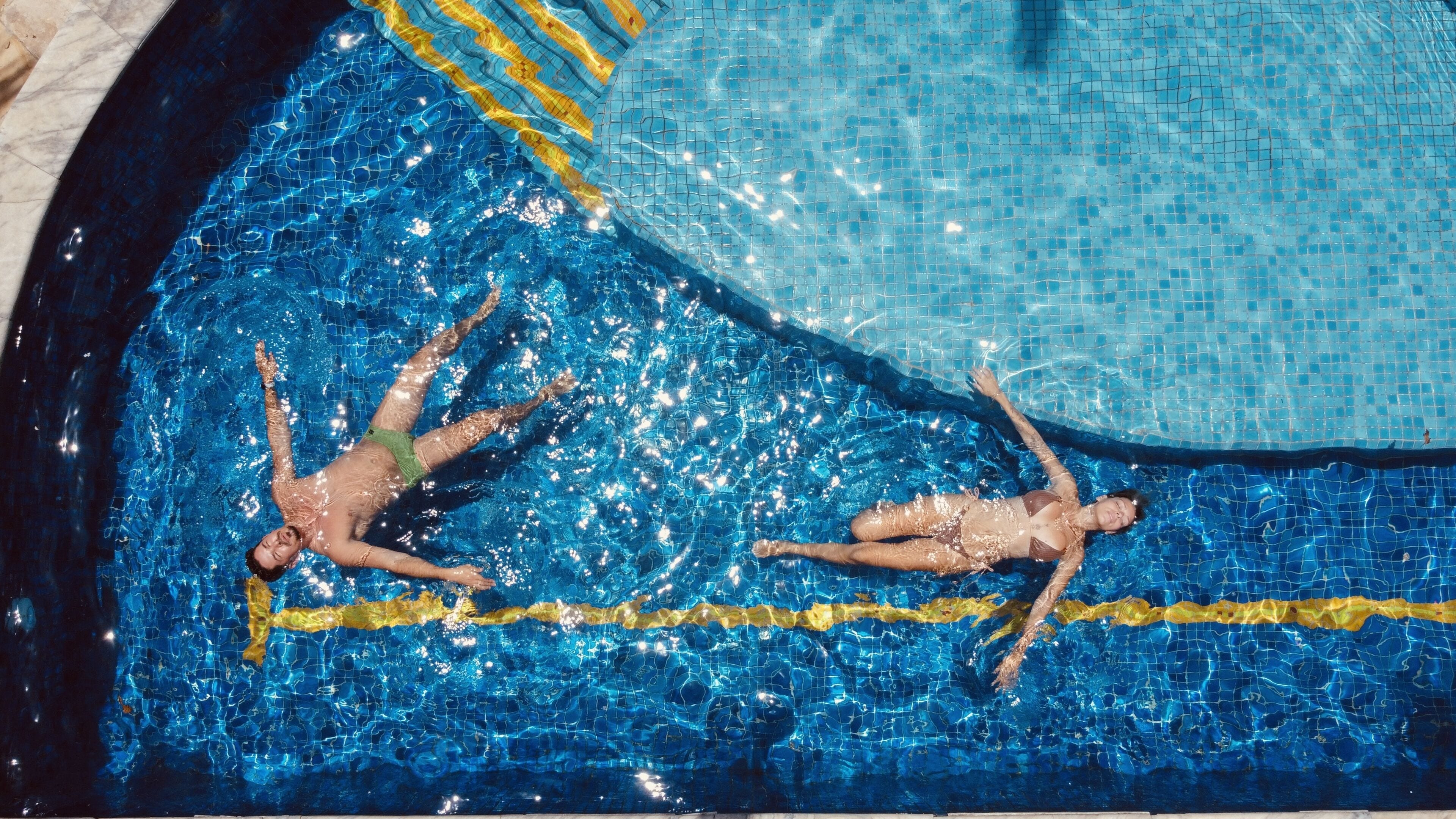 Una piscina con dos personas flotando en la superficie.
