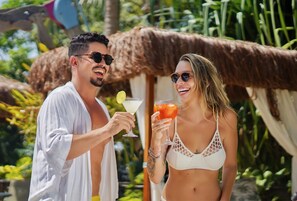 Two people holding drinks in a tropical setting with a thatched-roof structure. - ThalassaGarden Hotel - Pousada (Tibau do Sul)