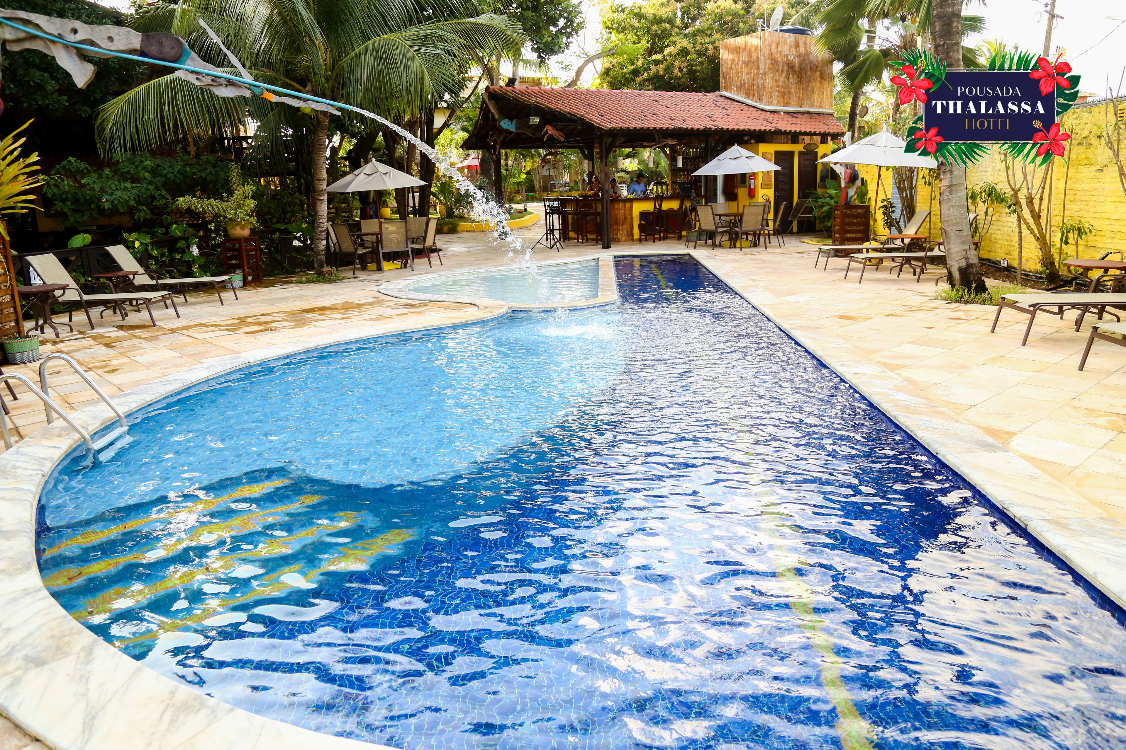 A swimming pool with lounge chairs and a bar area.