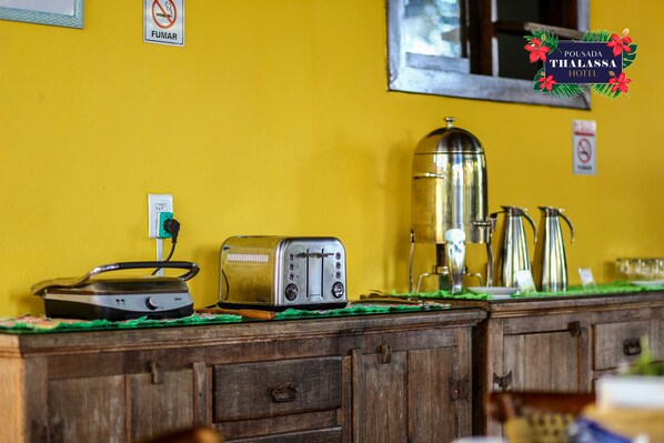 A kitchenette with a toaster, a kettle, and a coffee maker on a wooden counter.