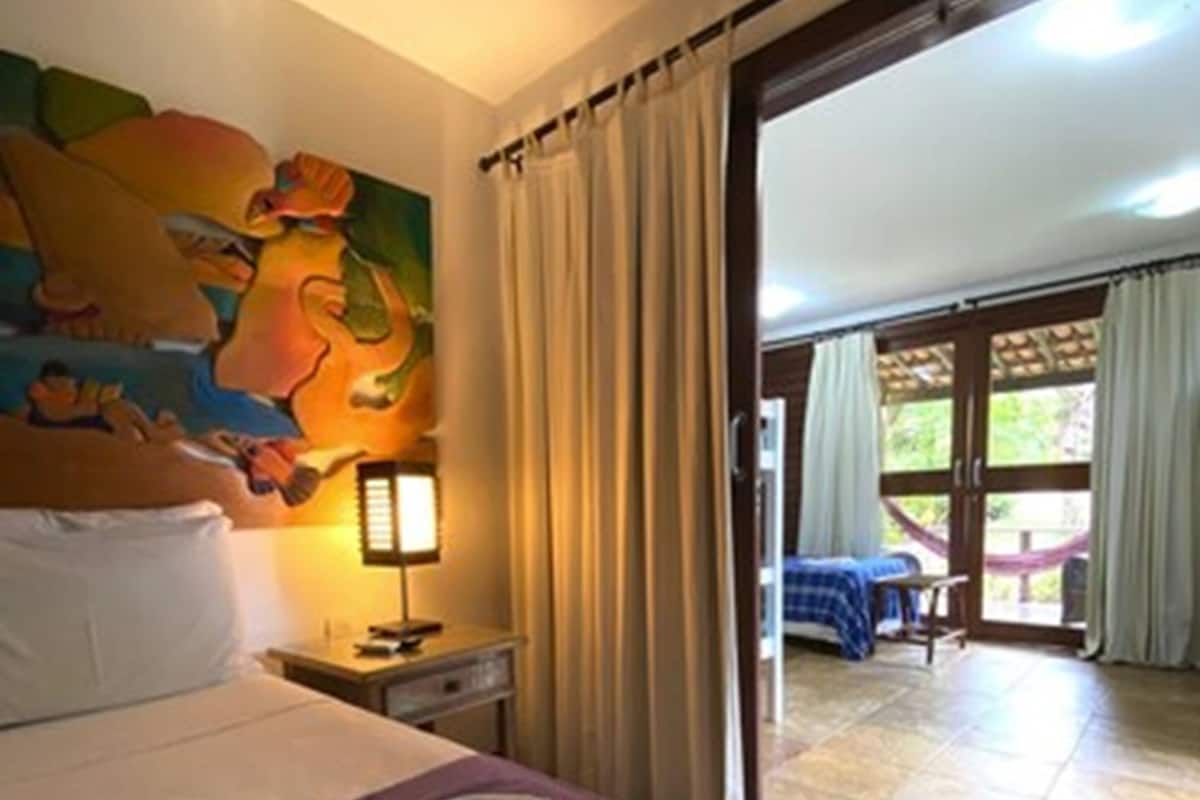 Une chambre d’hôtel avec un lit, un tableau au mur, une table de chevet et une vue sur un espace extérieur grâce à une porte coulissante.