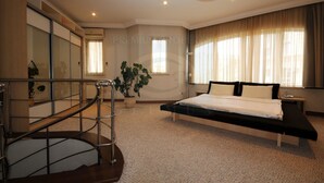 A modern bedroom with a large bed, a staircase with a metal railing, and a potted plant. - First Choice Apartments (Chisinau)
