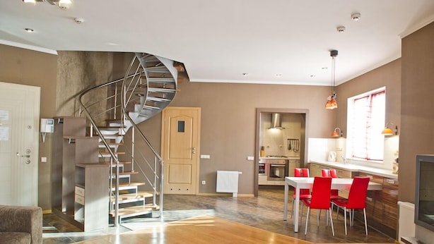 A modern interior with a spiral staircase, a dining area with red chairs, and a kitchen with a window. - First Choice Apartments (Chisinau)