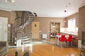 A modern interior with a spiral staircase, a dining area with red chairs, and a kitchen with a window. - First Choice Apartments (Chisinau)