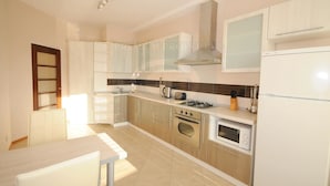 A modern kitchen with white cabinets, a gas stove, an oven, a microwave, and a sink. - First Choice Apartments (Chisinau)