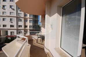 A balcony with a view of a multi-story building, a table, and a chair. - First Choice Apartments (Chisinau)
