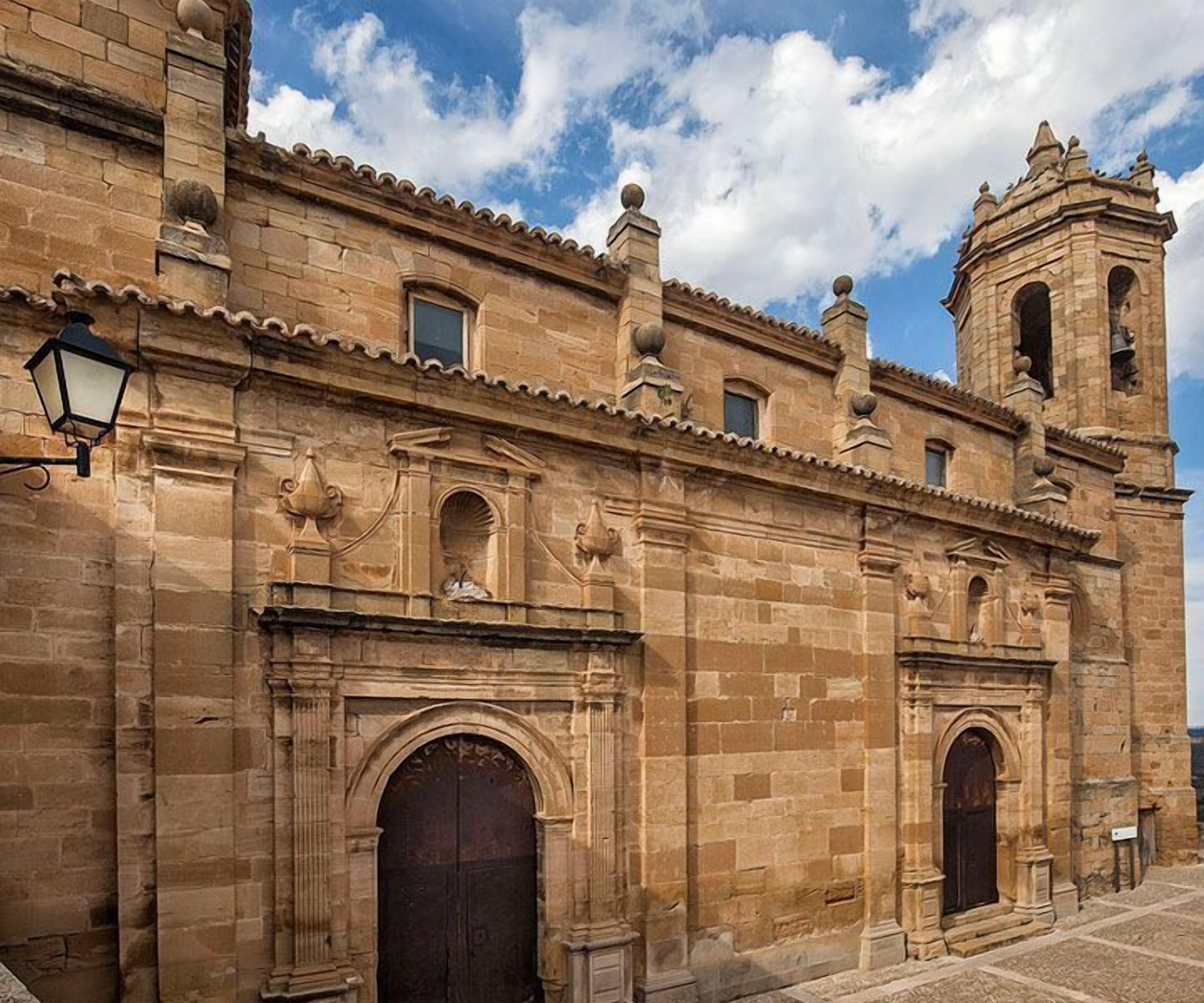 Un edificio histórico con una imponente torre de campanas y puertas en arco.