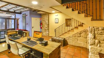 Un vestíbulo de hotel con un escritorio de madera, una computadora y una silla, una pared de piedra y una escalera.
