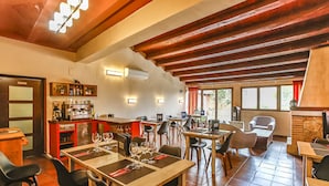 A restaurant with wooden beams, tiled floors, and multiple dining tables and chairs. - La Grancha (La Fresneda)