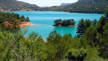 Un paisaje costero con un lago turquesa, rodeado de densos bosques y colinas verdes.