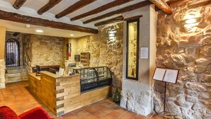 A rustic interior with stone walls, wooden reception desk, and a tiled floor. - La Grancha (La Fresneda)