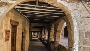 A corridor with stone walls and wooden beams, leading to an open area. - La Grancha (La Fresneda)