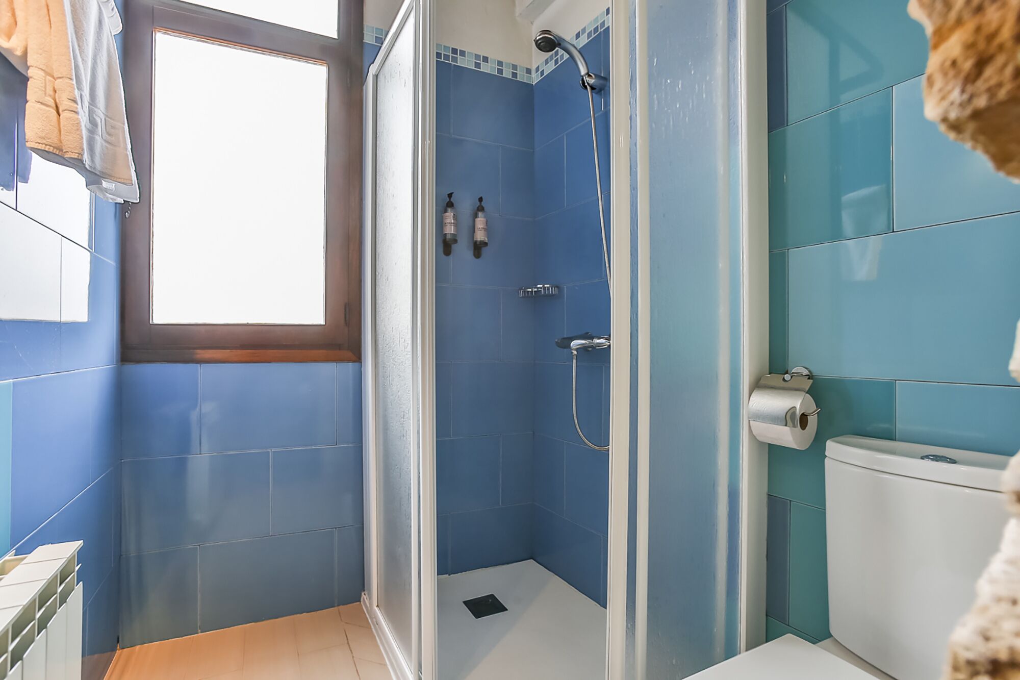 Un baño con ducha, inodoro y ventana.