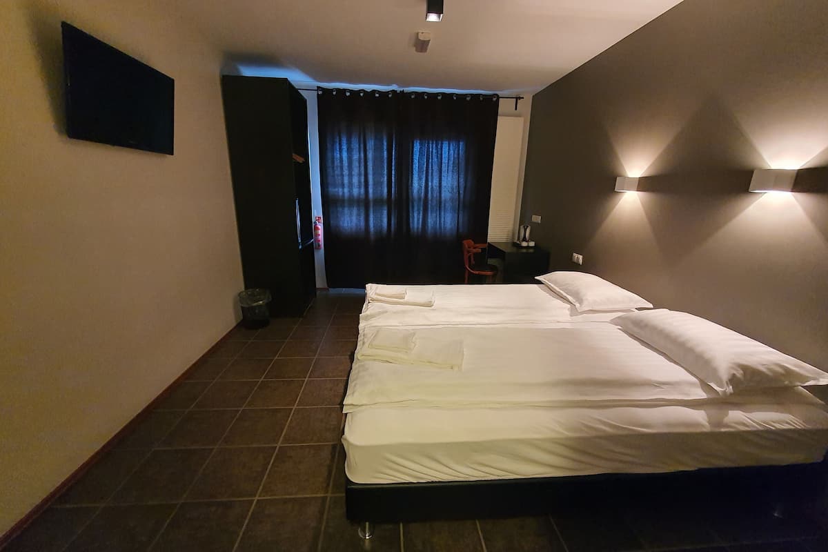 A hotel room with a bed, a chair, a desk, and a wall-mounted TV.
