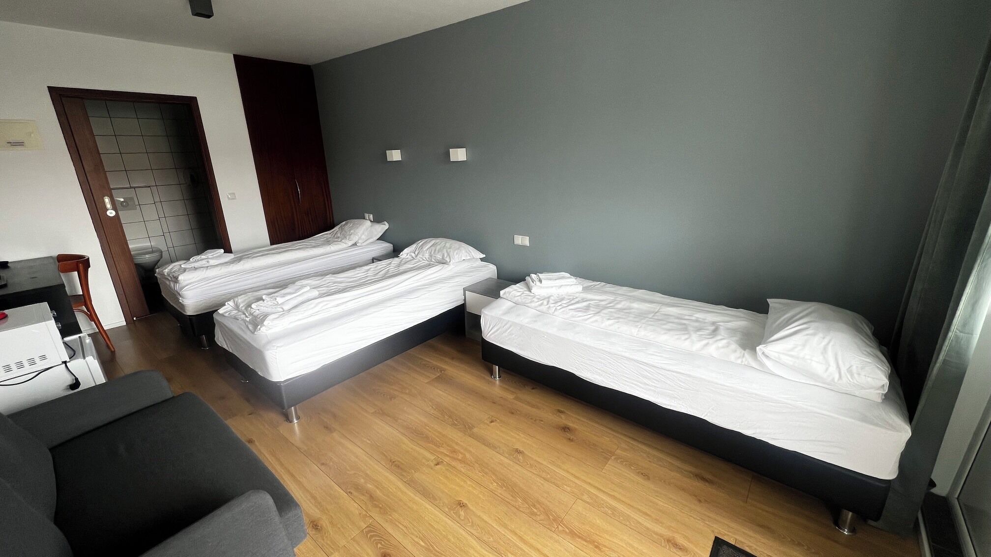 Ein Zimmer mit drei Betten, einem Schreibtisch und einem Stuhl.